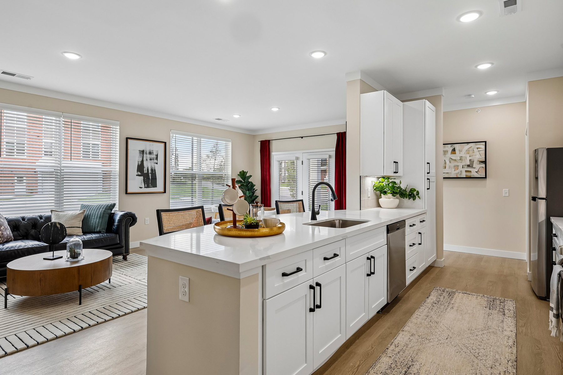 Open living room with seating beside a kitchen breakfast bar.