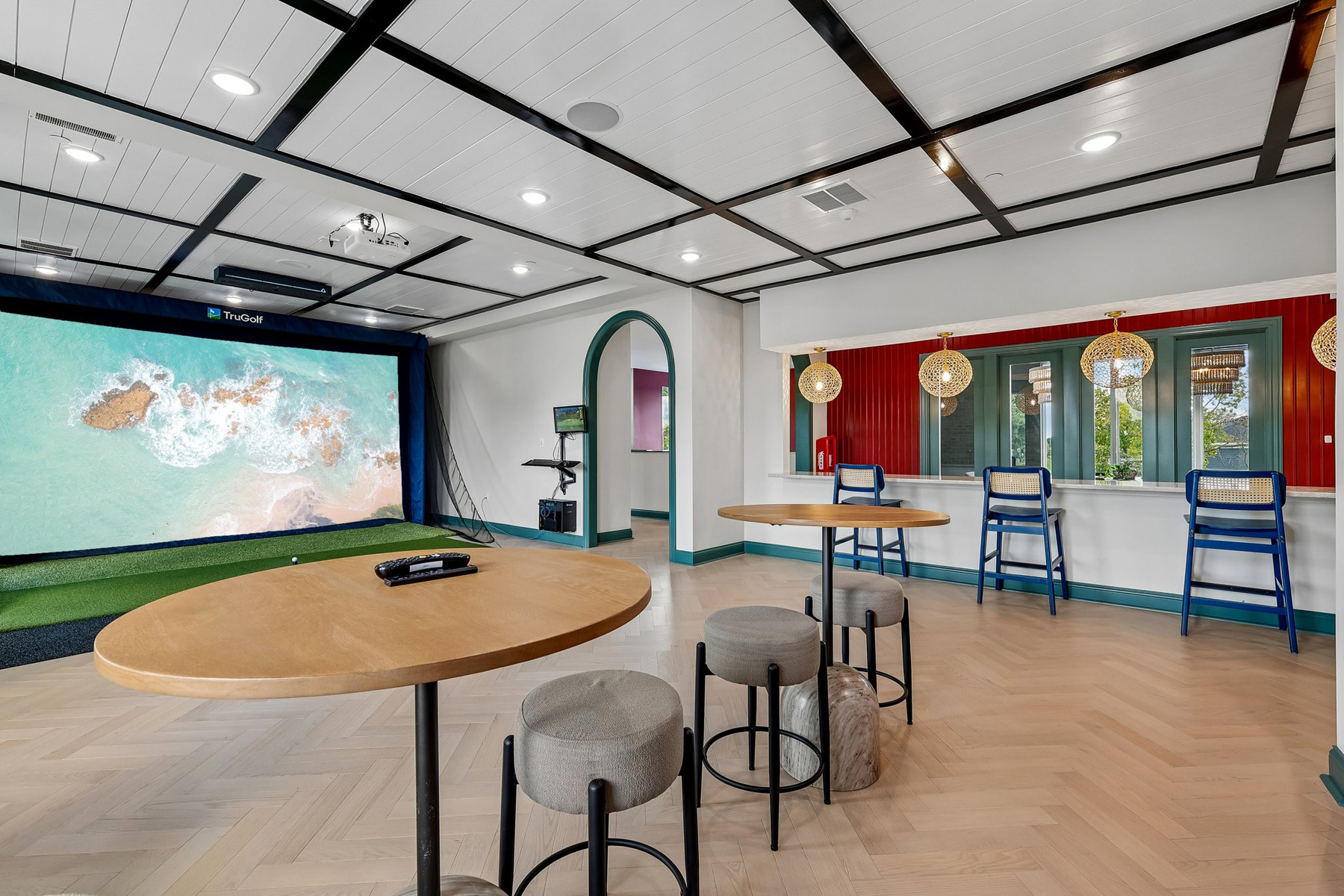 Clubhouse game room with a large golf simulator screen and counter seating.