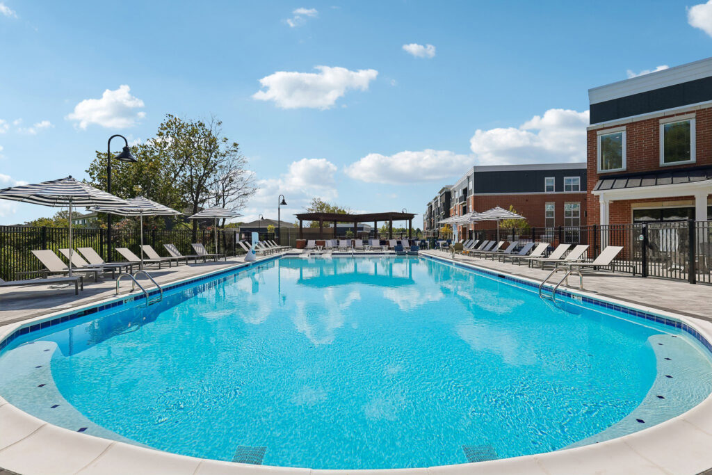 Pool deck with lounge chairs, umbrellas and a view of the clubhouse.